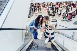 Two young women on escalator in shopping mall